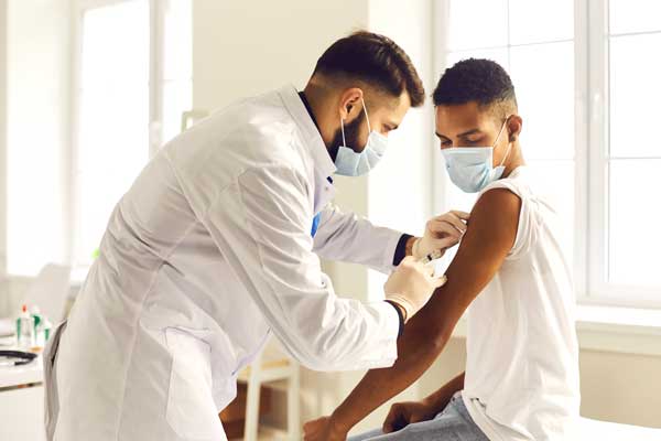 Male nurse administers vaccine to young boy