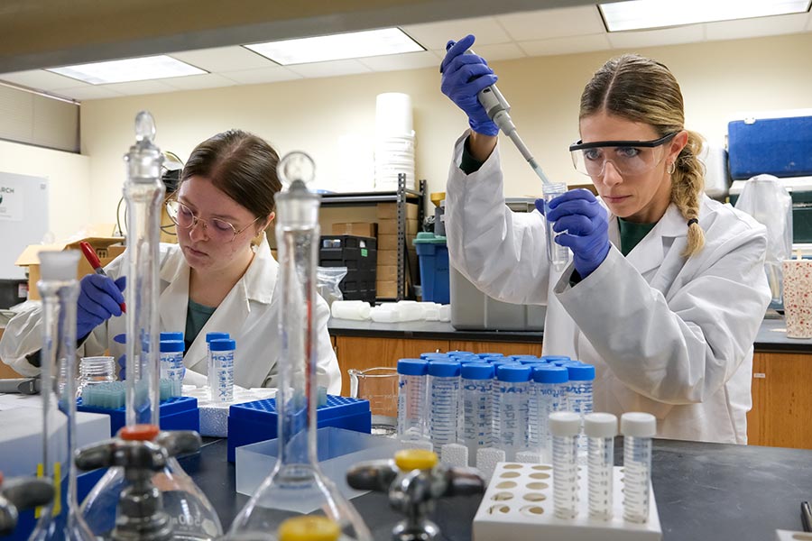 Two undergraduate water science research students prepare water samples in the research lab.