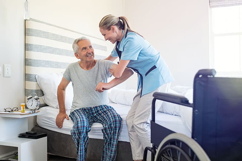 Caregiver helping an elderly man get out of bed