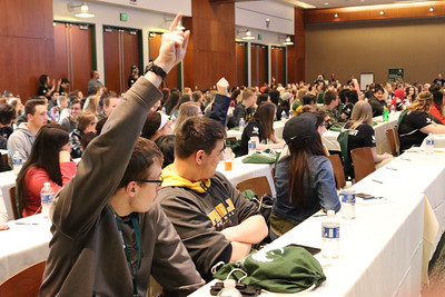 Students in a lecture hall with raised hands