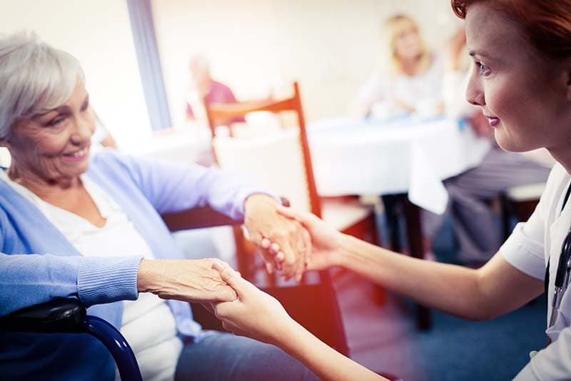 caregiver holding senior woman's hands