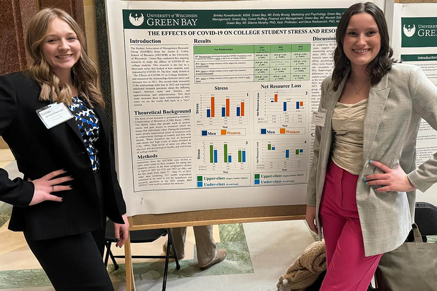 Two students in front of large informational poster