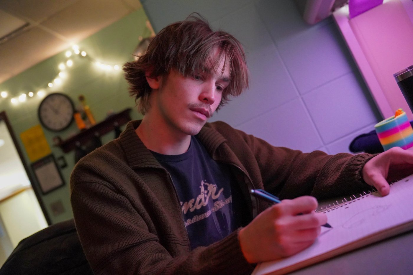 A graphic design student sketches in a notebook