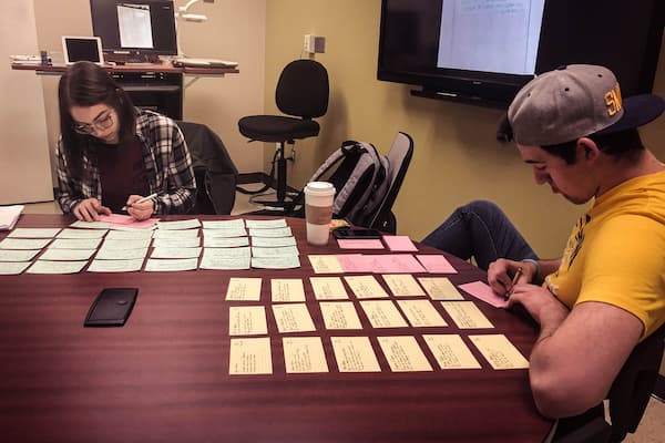 Male and female students use note cards to plan out writing