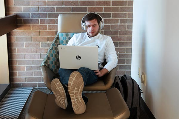Student studying online with headphones and a laptop in the library