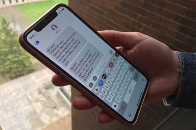 Hand with a mobile phone showing GB Alert text message notifications