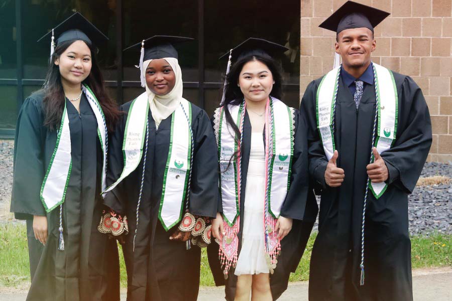 Four students standing together in graduation robes and hats