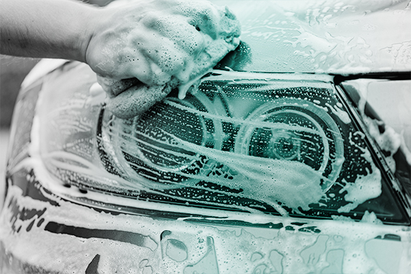 Closeup of a hand washing a headlight of a vehicle