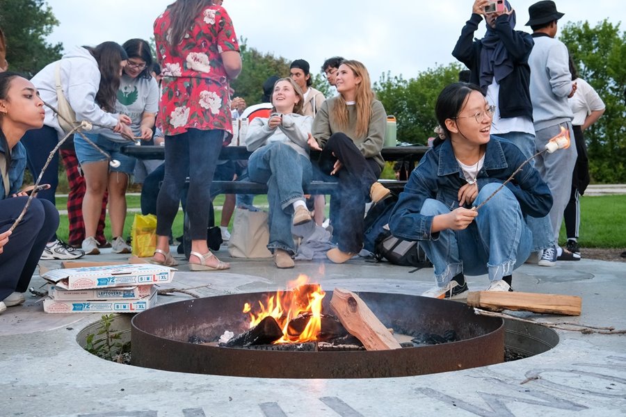 International students enjoy International Student Orientation by making smores around a firepit