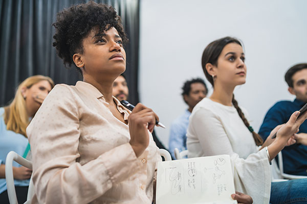 woman taking notes during a speaker presentation