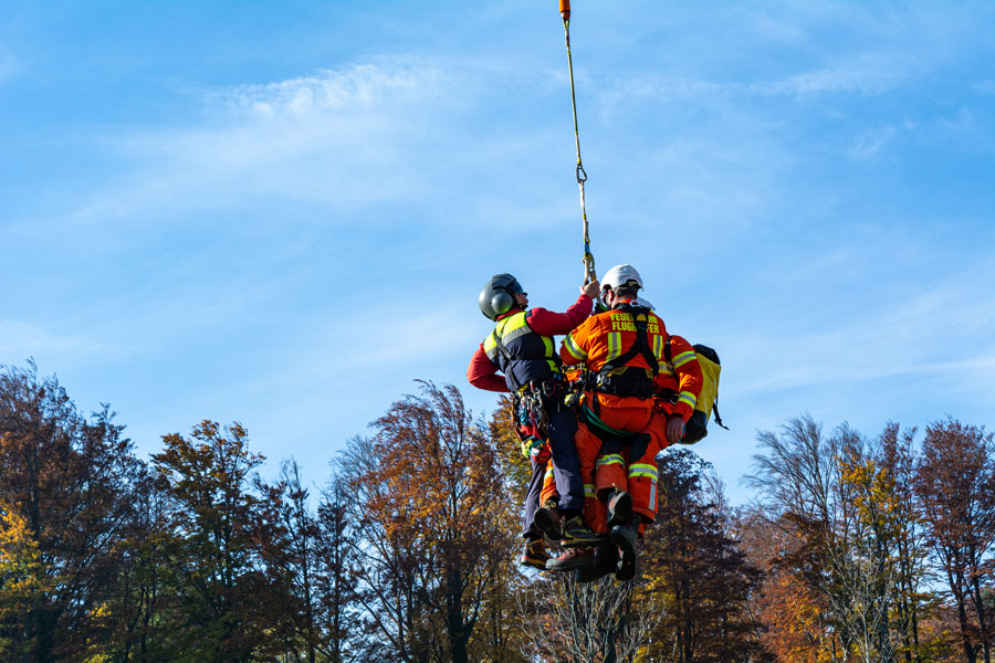 Emergency crew suspended from helicopter rescuing person