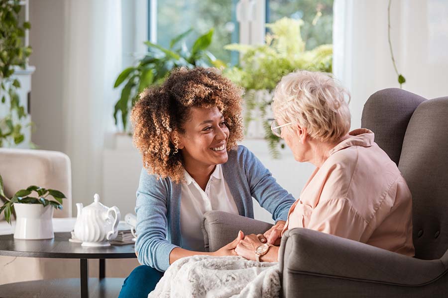 caregiver talking with senior woman sitting in chair