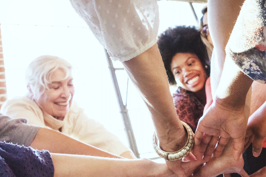 People with hands joined in the center of a circle