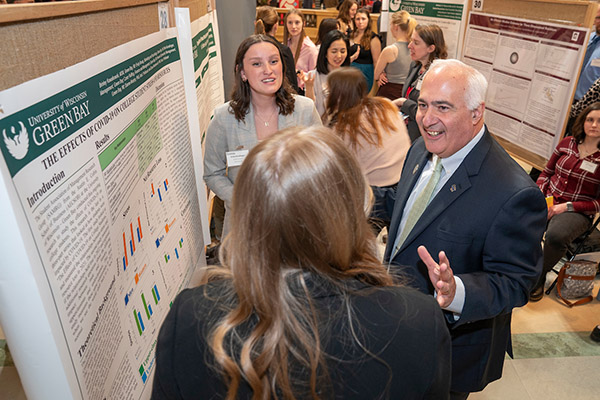 Group of people smiling and talking in front of research posters