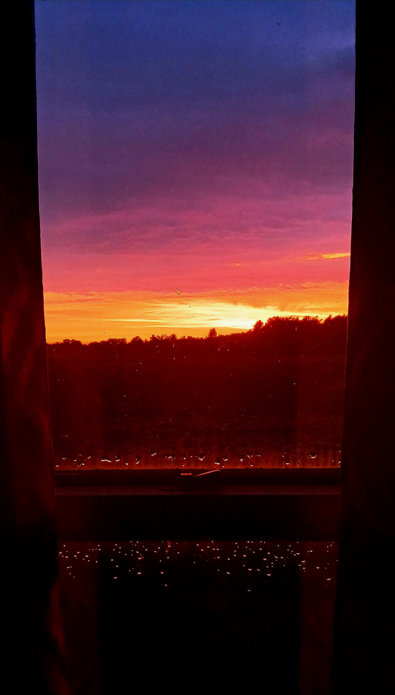 Photo of a brilliant sunset framed by a window.