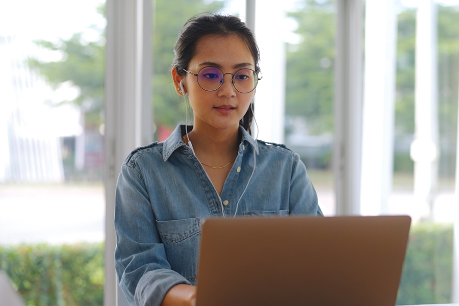 A young woman attending class from her laptop.