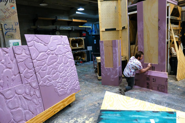 Student paints program set purple in the Scene Shop