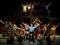 Many actors on stage with outstretched arms