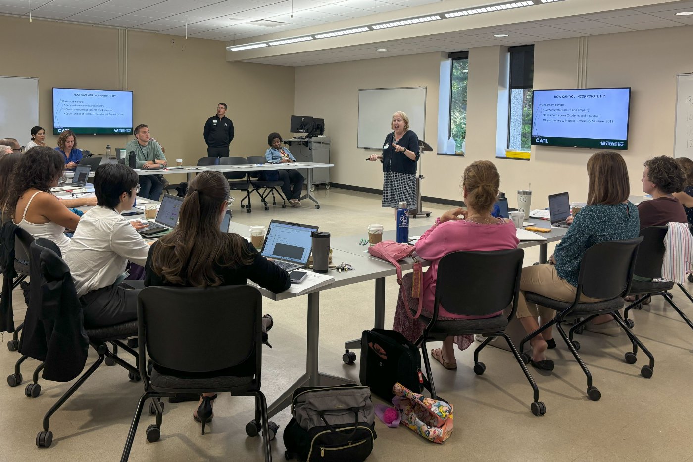 instructors in a classroom sitting in a circle with their laptops