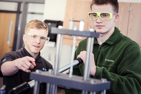 Two students test the breaking force of metal.