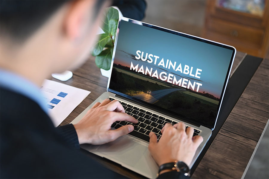 Man working on a laptop with the Sustainable Management screen