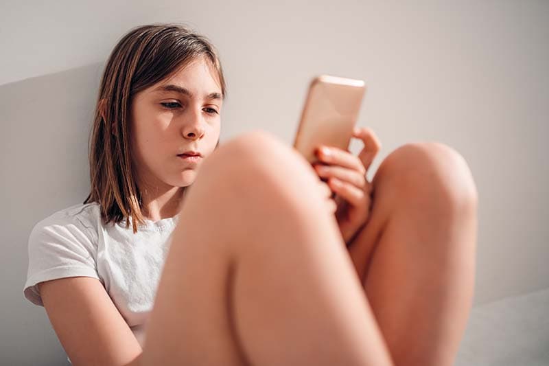 child sitting on floor looking at phone