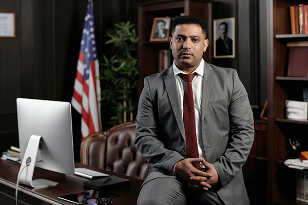 Lawyer sitting on front of desk with American flag behind him