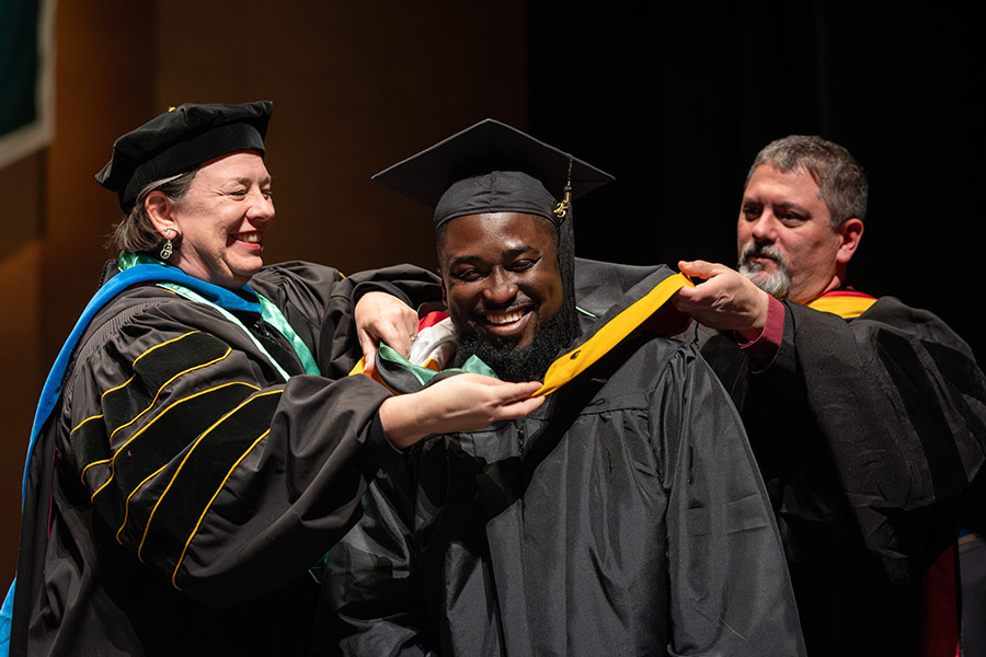 Student receiving a hood during graduation ceremony.