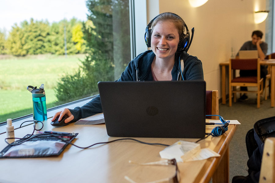 Student studying at desk near window in library