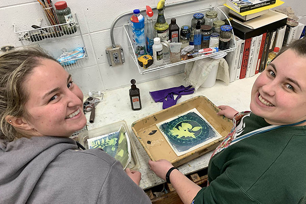 Two students working on printmaking projects