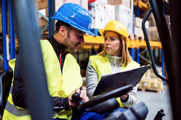 supply chain manager working in warehouse wearing hard hat
