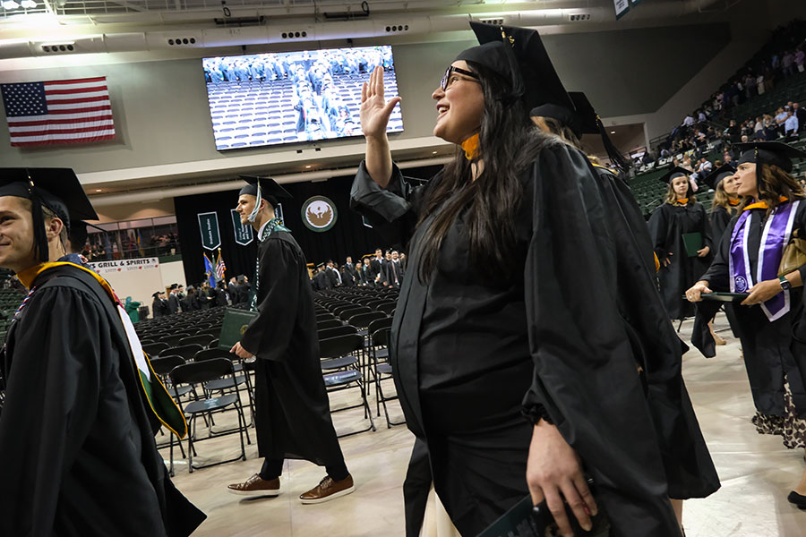 A female graduate waves to her family at commencement