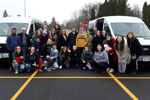 Group of students pose for photo in parking lot