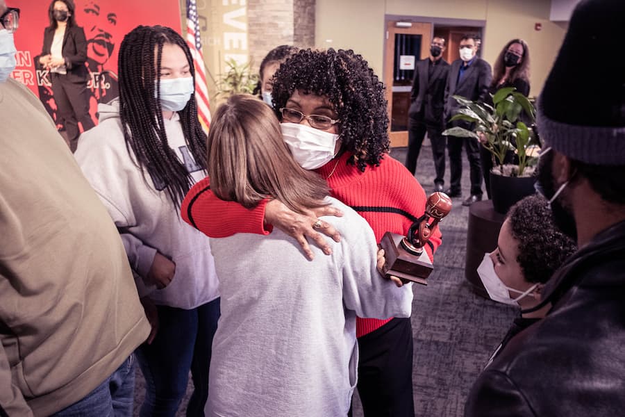 African American female hugs friend after receiving acknowledgement at MLK event