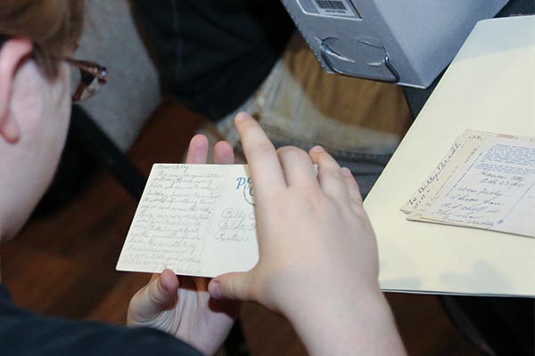 Student reading an archival postcard, holding it carfully by the edges