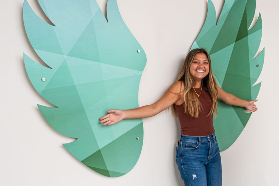 Student poses with phoenix wings wall art