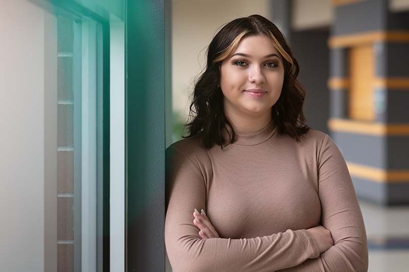 Haley with arms crossed leaning against wall