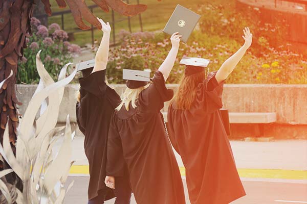 students taking photos by phoenix statue after commencement