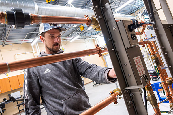 Engineering student behind framework of pipes