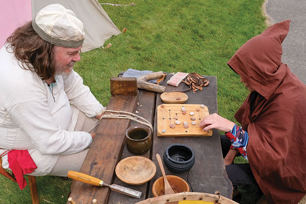 Two people sit at a table playing hnefatafl.