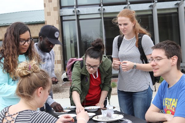 "Diverse group of students participate in a beading activity at a multicultural fair