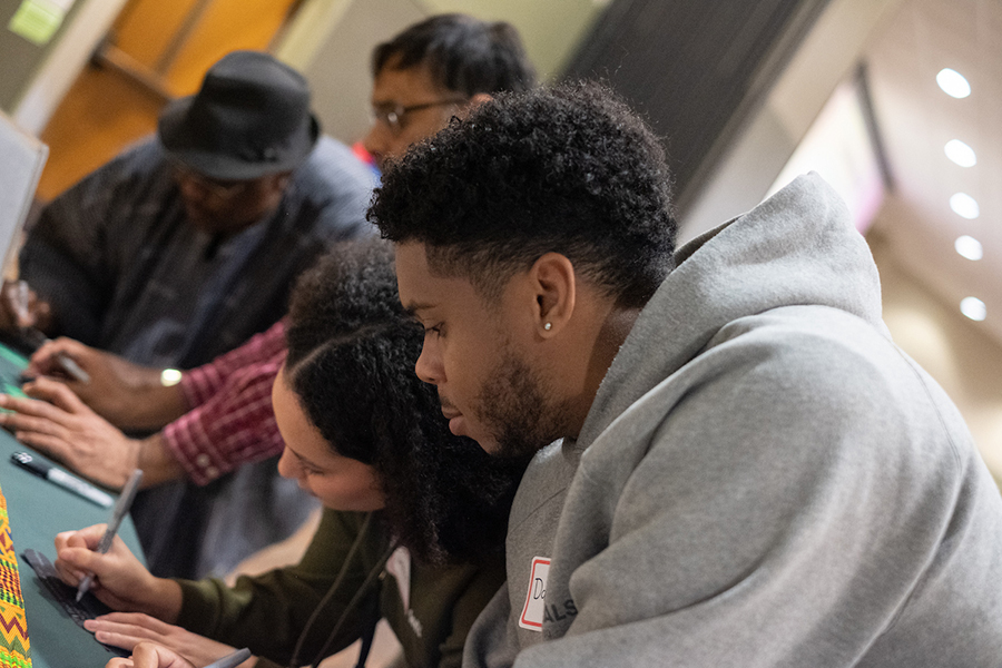 Four people stand at a table and work on an activity