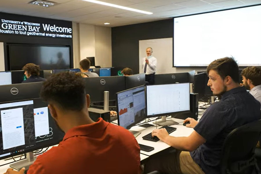 Students sitting in a computer lab discussing the stock market.