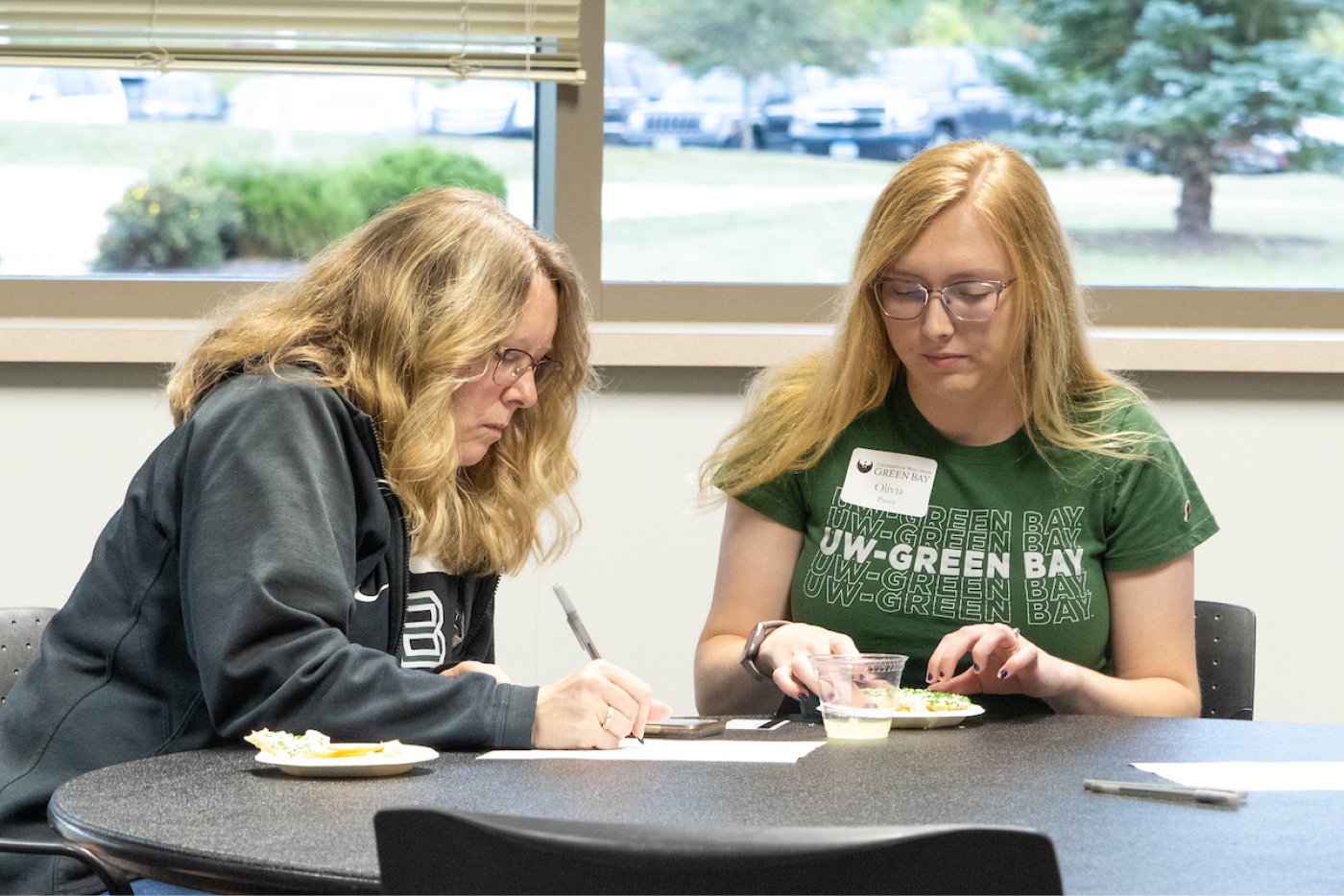 A student and their parent sit at a table during an event at Family Weekend