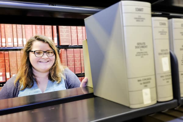 Student looking through open bookshelf