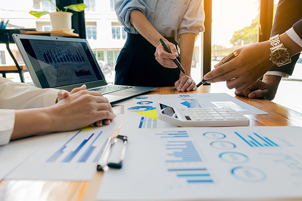 People working with financial charts spread about a desk