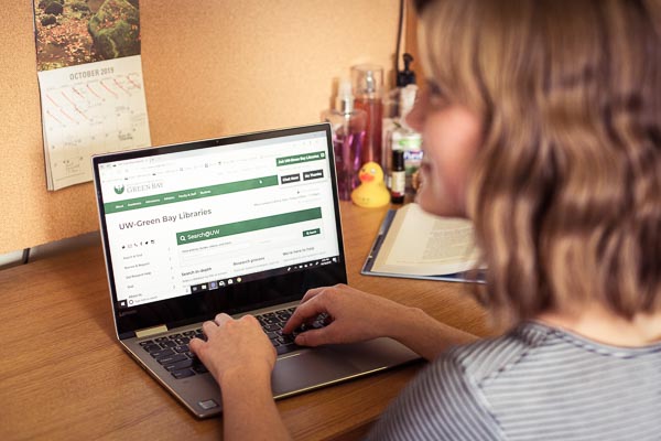 Student using a laptop at her dorm room desk