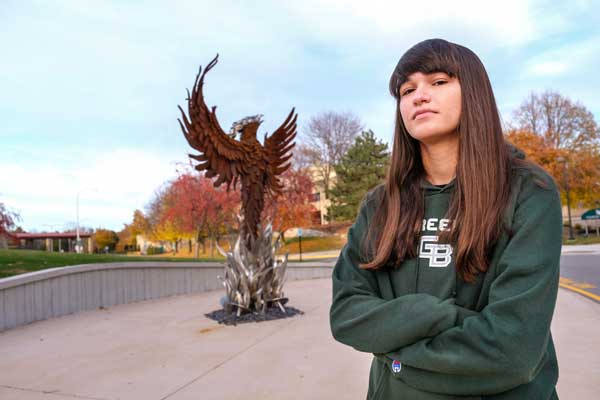 Students poses in front of UWGB Phoenix Sculpture