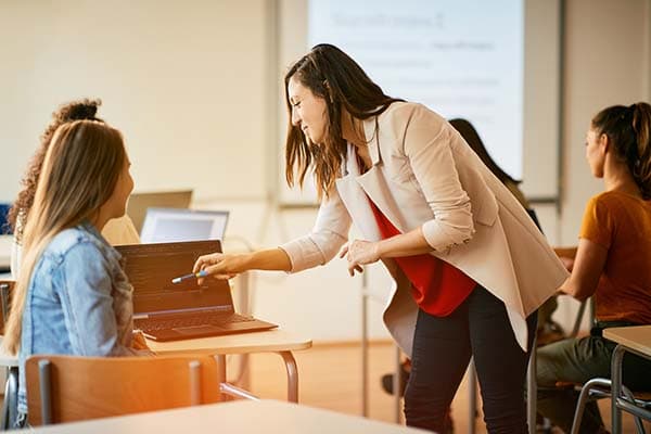 woman teacher looking at laptop screen with student