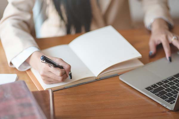 businesswoman writing goals in notebook